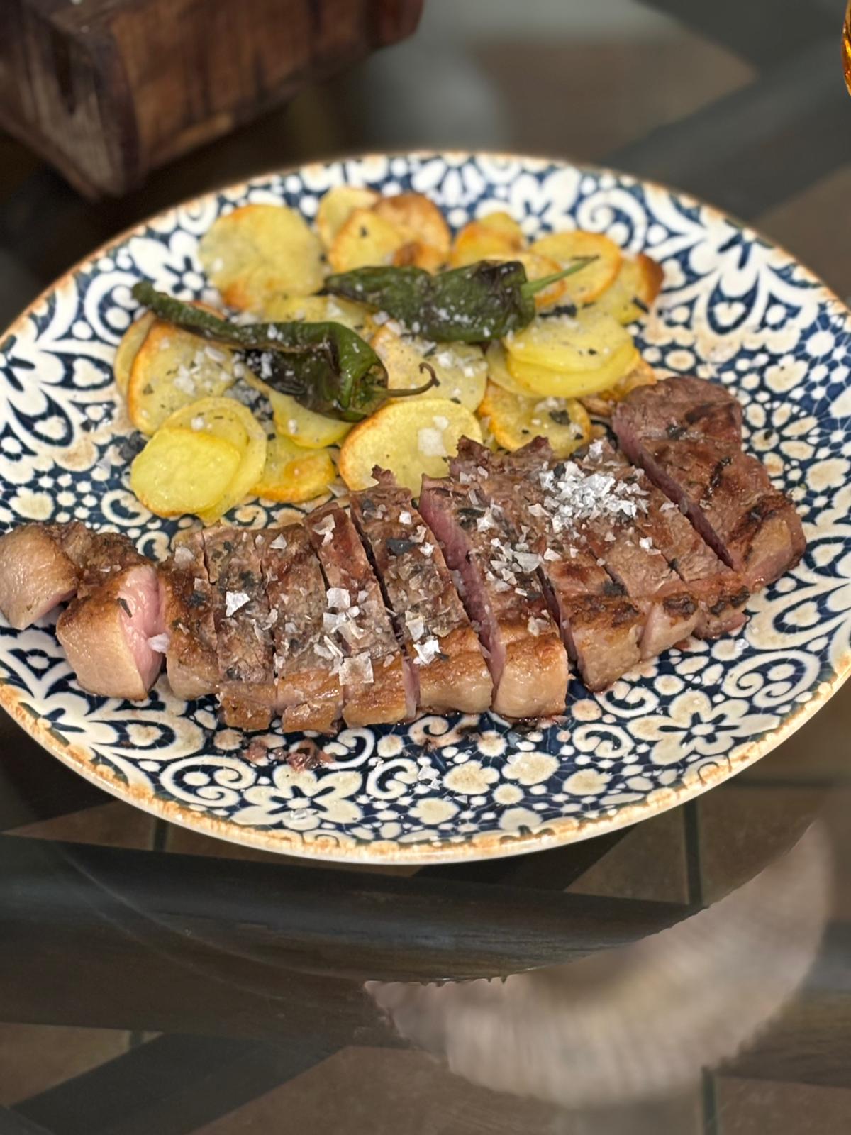 Presa ibérica con patatas panaderas y padrón